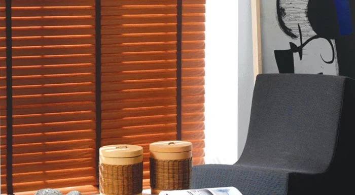 Warm orange aluminum blinds beside an armchair