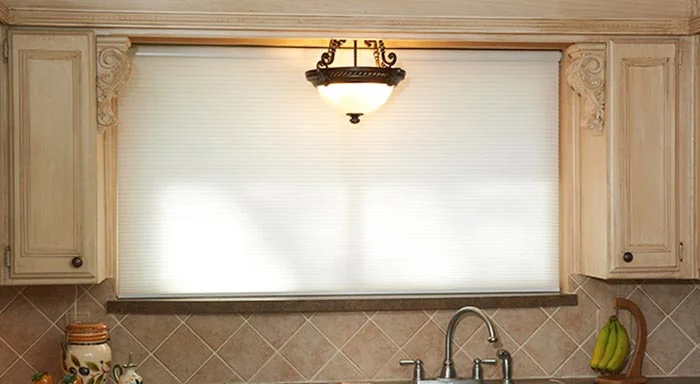White cellular shade covering a kitchen window